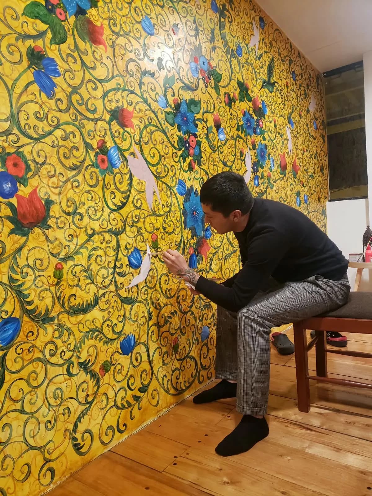 Detalle de Joan Alfaro añadiendo flores a un mural del hotel